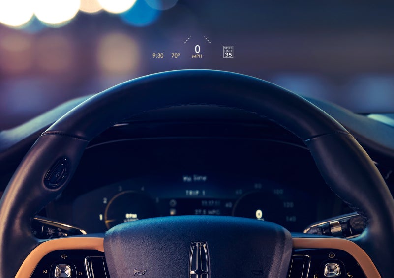 The available head-up display projects data on the windshield above the steering wheel inside a 2022 Lincoln Corsair as the driver navigates the city at night | Klaben Lincoln in Kent OH