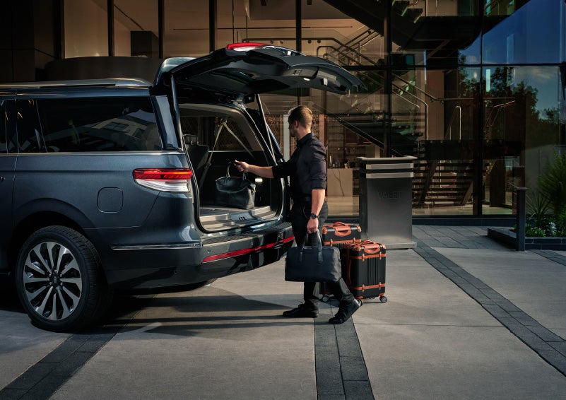 A valet is unloading luggage from the rear cargo area of a 2022 Lincoln Navigator SUV | Klaben Lincoln in Kent OH