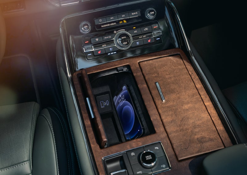 A smartphone is charging on the wireless charging pad in the front center console cubby | Klaben Lincoln in Kent OH
