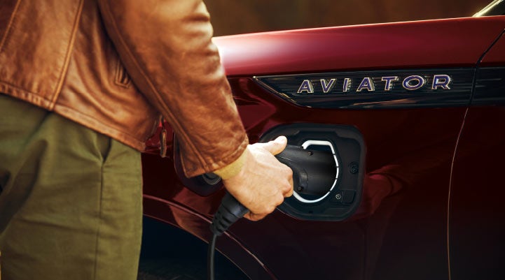 A hand is shown plugging in the charger into the charging port of a 2021 Lincoln Aviator | Klaben Lincoln in Kent OH