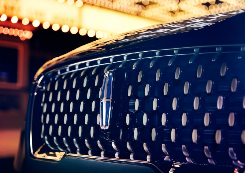 The Corsair Grand Touring grille shows floating chrome ovals that catch the glowing light of a theater marquee and frame the distinctive Lincoln Star | Klaben Lincoln in Kent OH