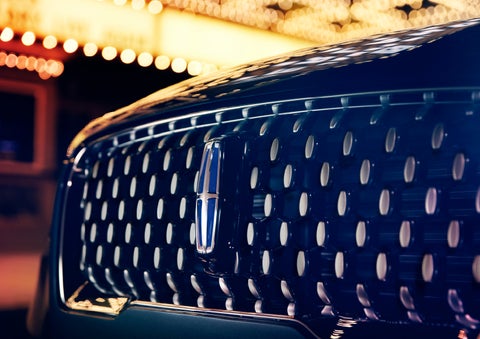The Corsair Grand Touring grille shows floating chrome ovals that catch the glowing light of a theater marquee and frame the distinctive Lincoln Star | Klaben Lincoln in Kent OH