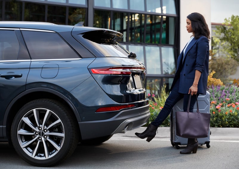A woman with luggage and a bag opens the available hands-free liftgate by kicking her foot under the bumper | Klaben Lincoln in Kent OH