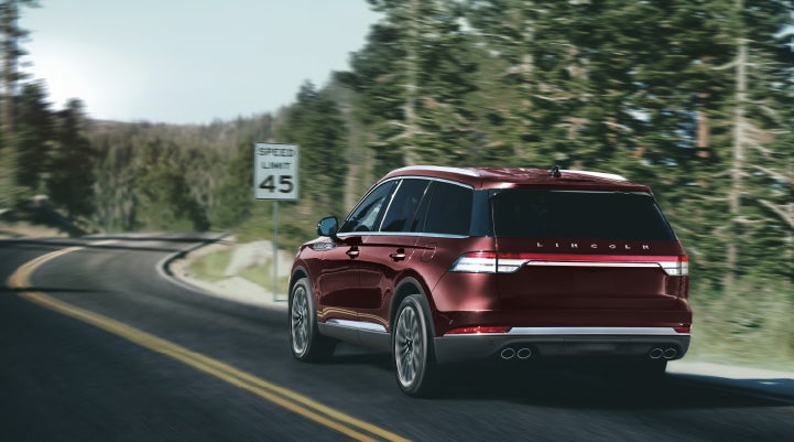 A 2024 Lincoln Aviator® SUV is being driven on a winding mountain road | Klaben Lincoln in Kent OH
