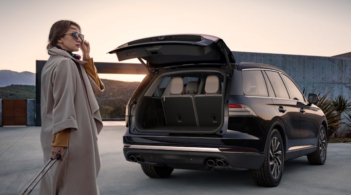 A woman approaches a 2026 Lincoln Aviator® SUV with its rear liftgate open. | Klaben Lincoln in Kent OH