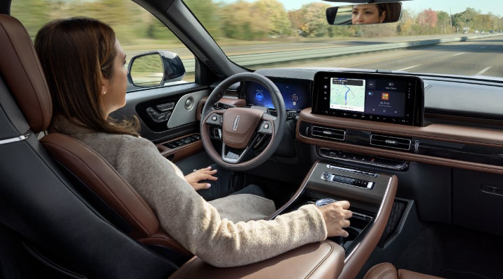 A 2026 Lincoln Aviator® SUV is being driven hands-free on a highway near a forest | Klaben Lincoln in Kent OH