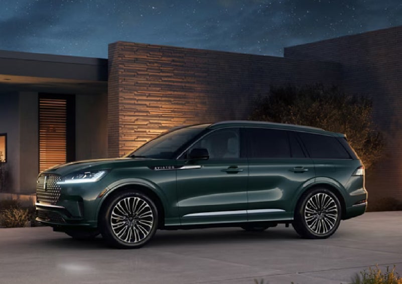 A green 2027 Lincoln Aviator® SUV is parked outside a contemporary home. | Klaben Lincoln in Kent OH