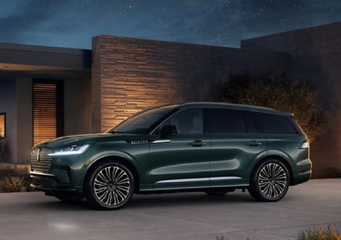 A green 2027 Lincoln Aviator® SUV is parked outside a contemporary home. | Klaben Lincoln in Kent OH