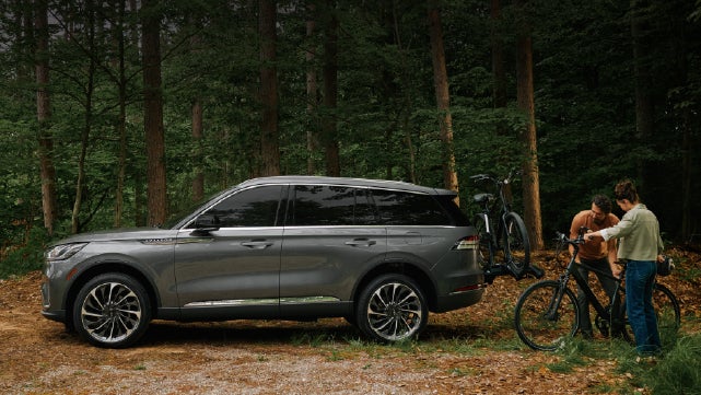 A father and son load e-bikes on a bike rack attached to a 2027 Lincoln Aviator® SUV. | Klaben Lincoln in Kent OH