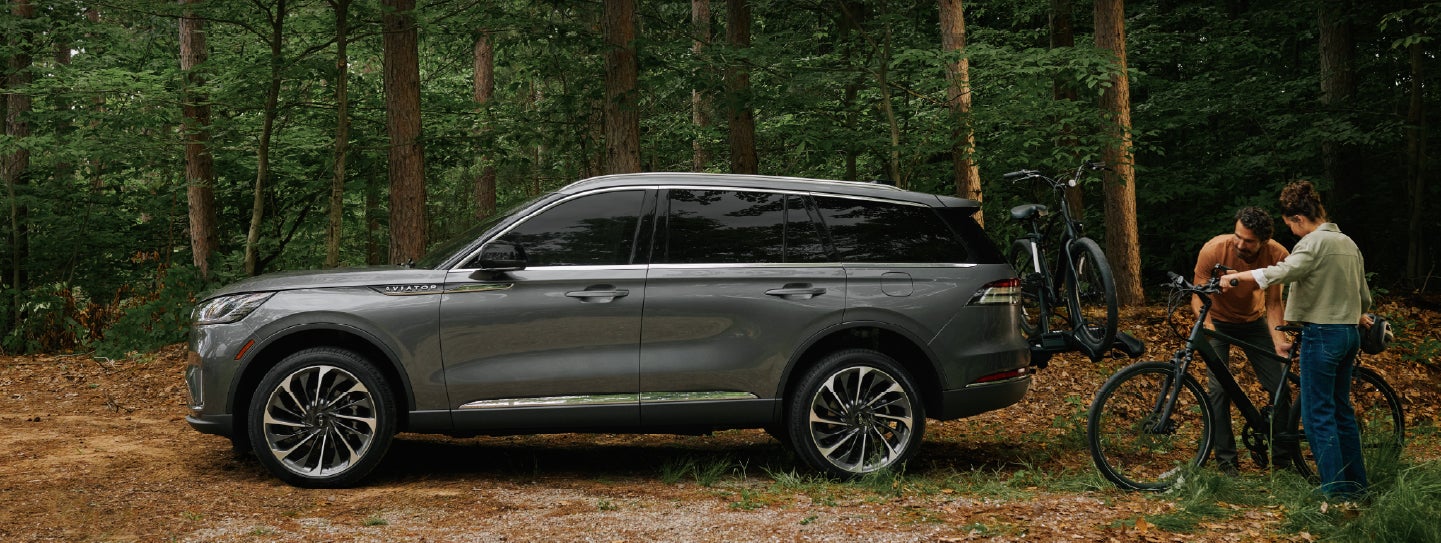 A father and son load e-bikes on a bike rack attached to a 2027 Lincoln Aviator® SUV. | Klaben Lincoln in Kent OH